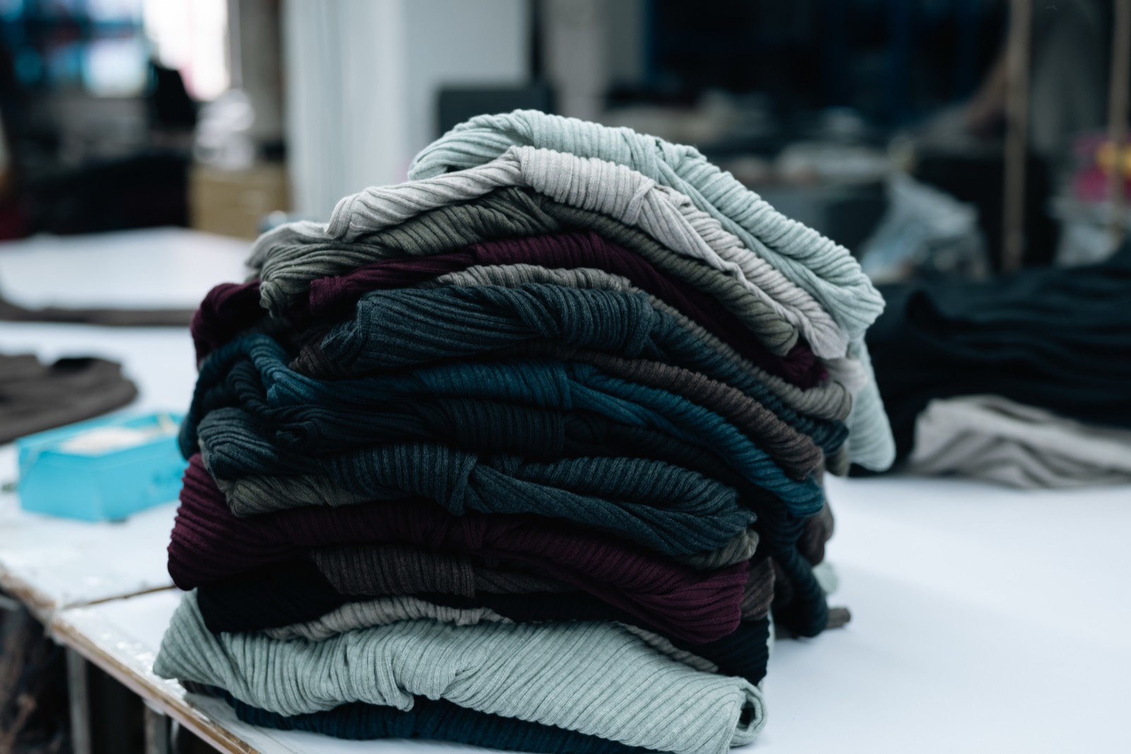 Stack of folded ribbed knitwear in grey, navy, burgundy and cream