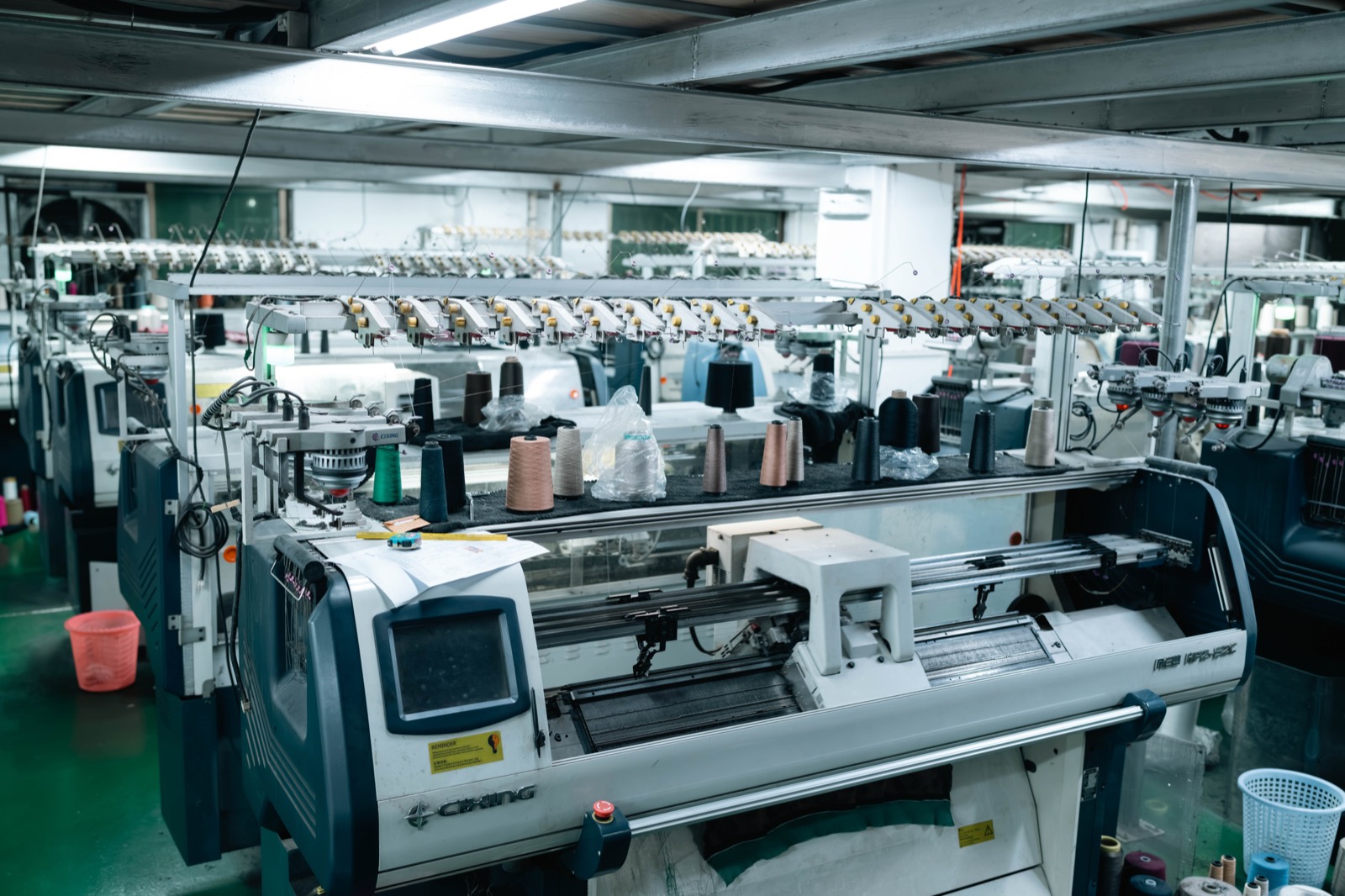 Rows of computerised flat knitting machines running in the knitting hall