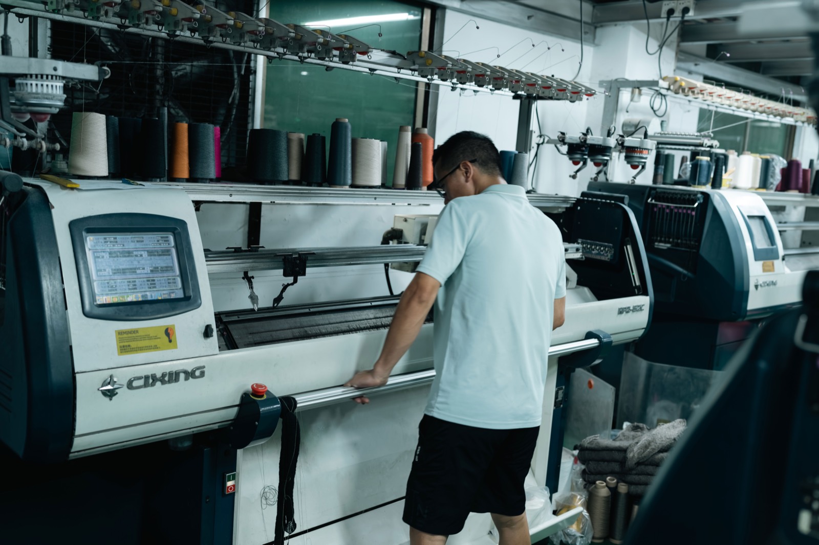 Operator working at the control panel of a flat knitting machine