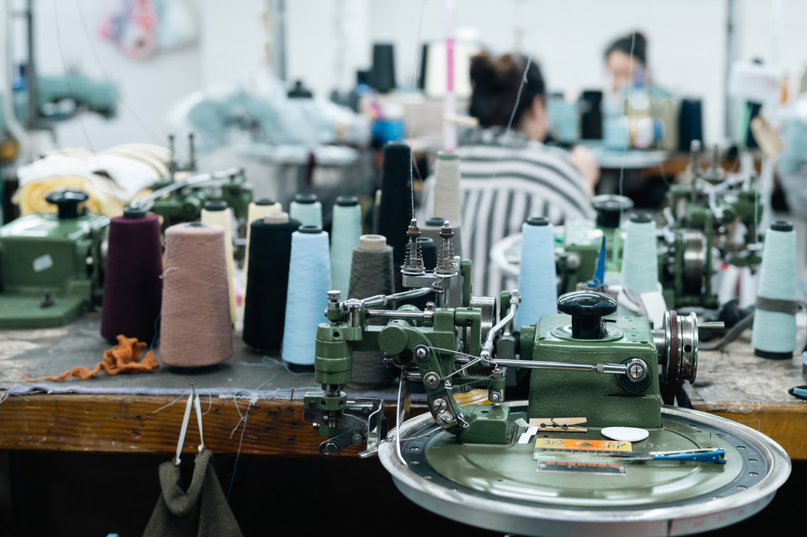 Linking machine dial on a work bench with cones of yarn behind it