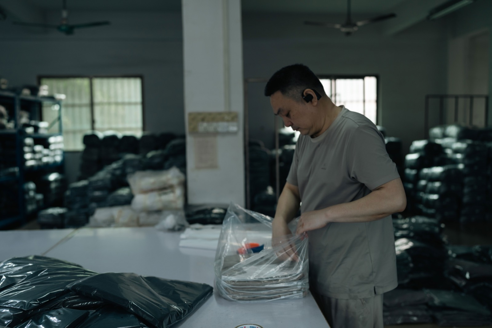Operator bagging folded garments at a packing table