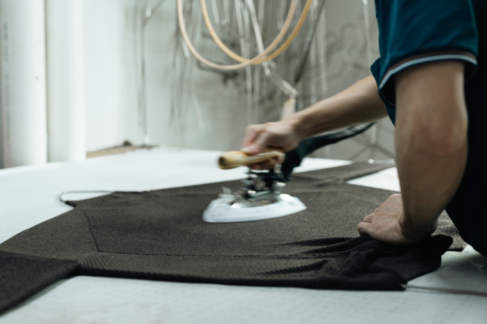 Close-up of a steam iron being worked across a dark brown knitted panel