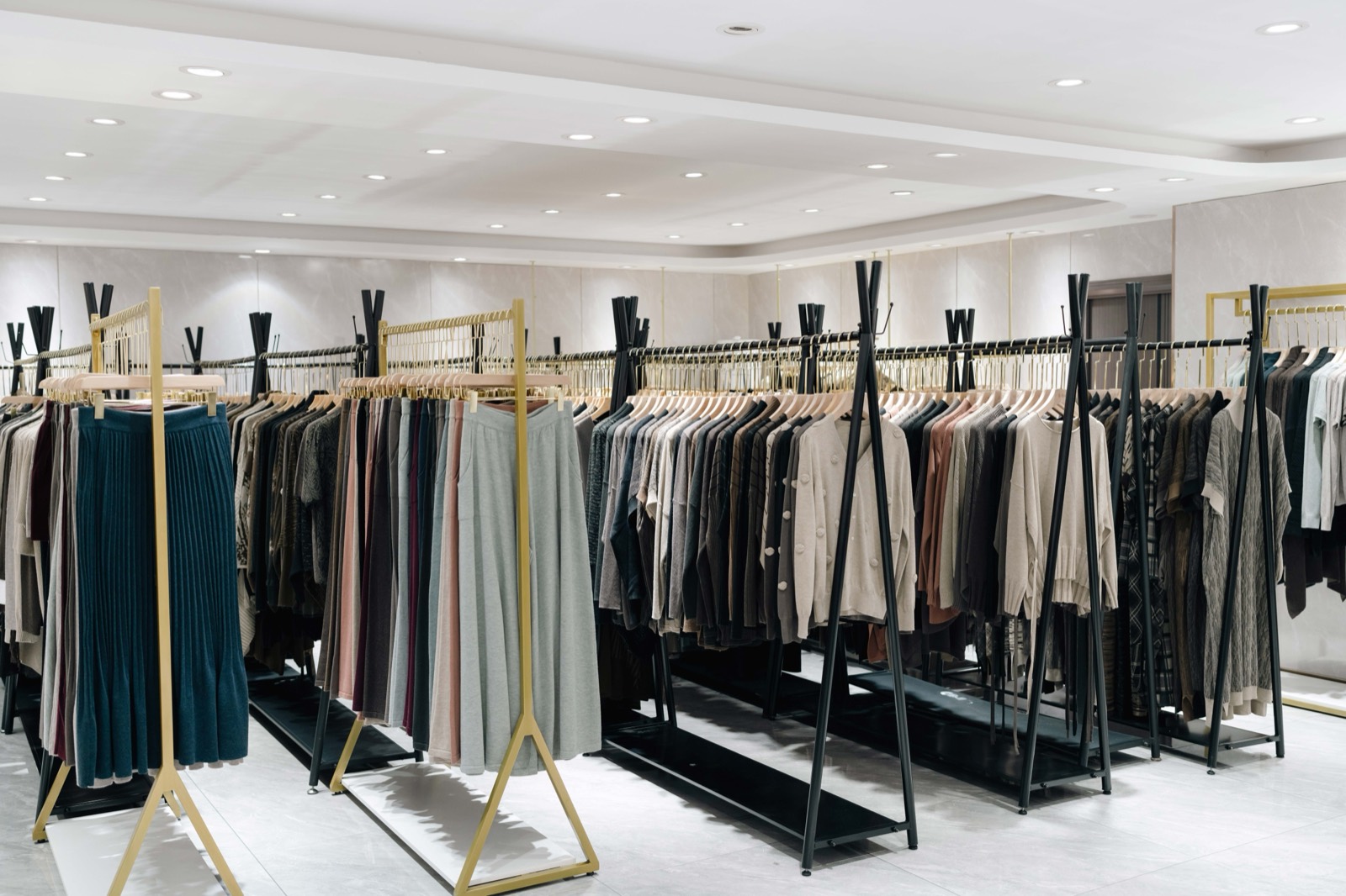 Showroom rails hung with knitwear in earth tones under downlights