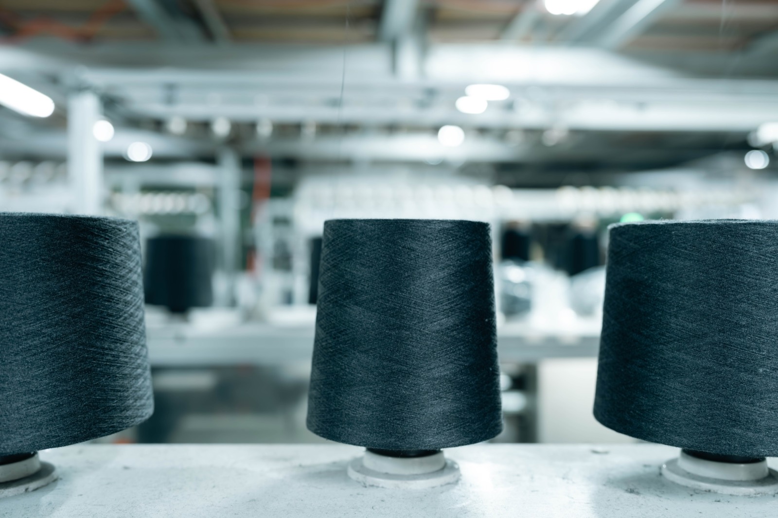 Cones of dark grey yarn on a winding frame