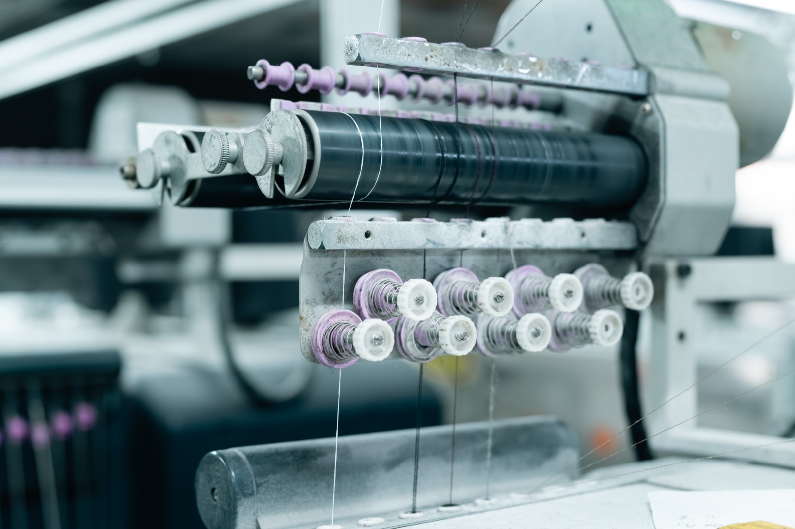 Close-up of the yarn feeders and tension discs on a knitting machine